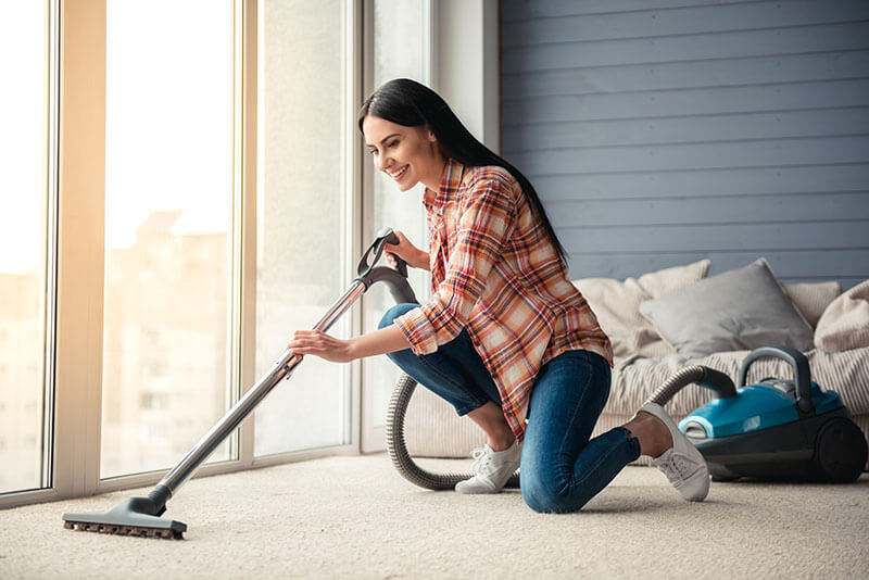 Woman performing routine carpet vacuum | The L&L Company