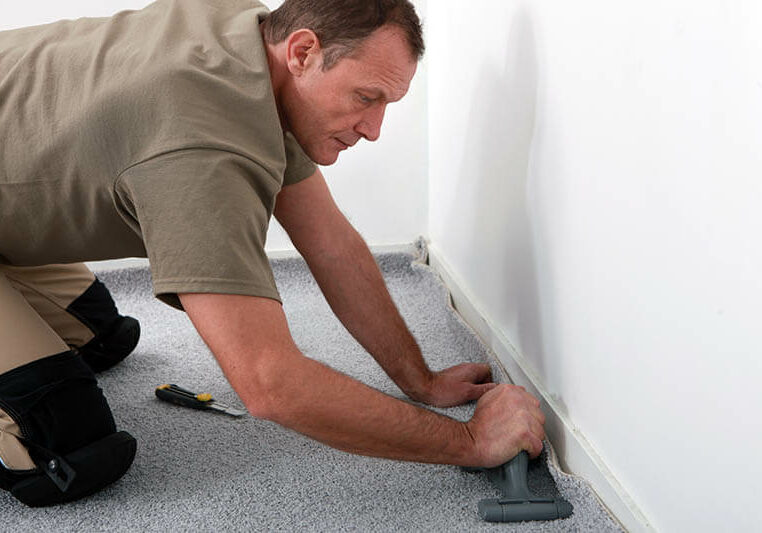 Worker installing carpet on floor | The L&L Company